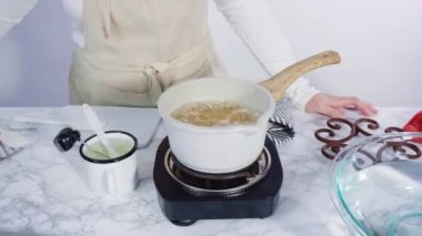 Adım adım. Küçük elektrikli ocağın üzerinde küçük bir tencerede karamelize şeker.