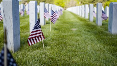 Denver, Colorado, ABD-26 Mayıs 2019 - Anma Günü 'nde Fort Logan Ulusal Mezarlığı' nda beyaz mermer mezar taşlarının yanında küçük Amerikan Bayrakları.