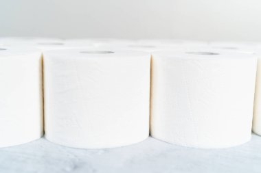 Gri arka planda yeni beyaz tuvalet kağıdı ruloları.