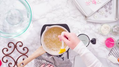 Düz yatıyordu. Adım adım. Küçük elektrikli ocağın üzerinde küçük bir tencerede karamelize şeker.