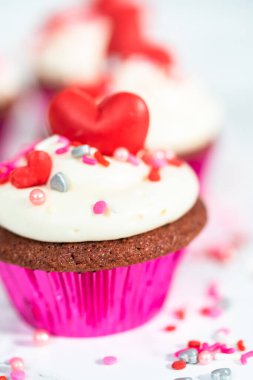 Krem peynirli kırmızı kadife kekler ve kalp ve öpücük şeklinde kırmızı çikolatalarla süslemeler..