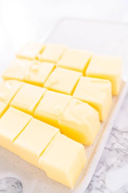 İtalyan kreması hazırlamak için tuzsuz tereyağı çubukları küp şeklinde kesilmiş..