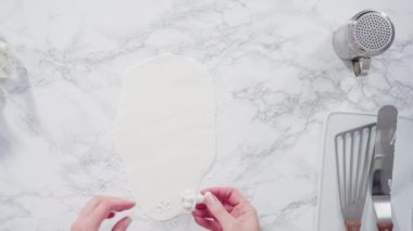 Mermer tezgahın üzerindeki beyaz fondanla kar tanelerini keserek..