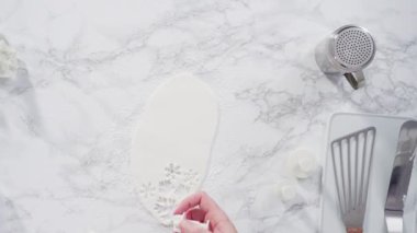 Mermer tezgahın üzerindeki beyaz fondanla kar tanelerini keserek..