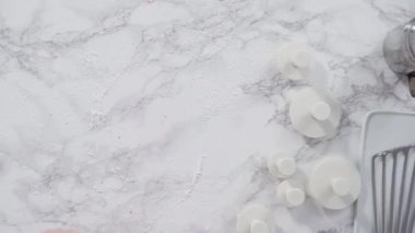 Mermer tezgahın üzerindeki beyaz fondanla kar tanelerini keserek..