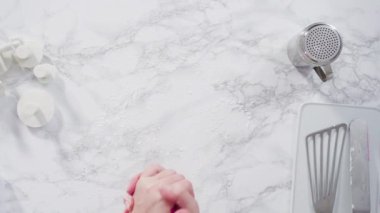 Mermer tezgahın üzerindeki beyaz fondanla kar tanelerini keserek..