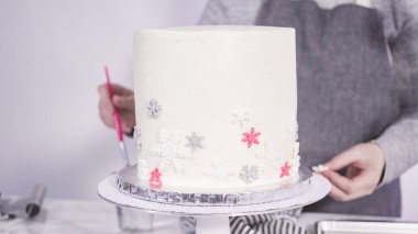 Adım adım. Yuvarlak funfetti pastasını pembe ve beyaz fondant kar taneleriyle süslüyorum..