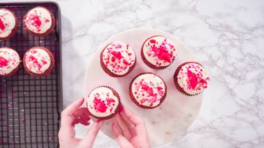Düz yatıyordu. Adım adım. Mermer pasta standında kırmızı kadife kekler düzenlemek..