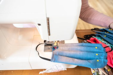 Koronavirüs salgını için dikiş makinesiyle pamuk yüz maskesi dikiyorum..