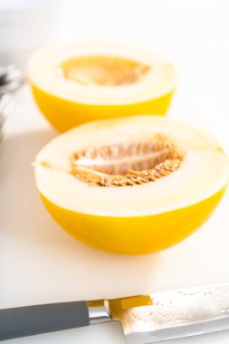 Beyaz kesme tahtasında kaygan altın çiğ taneli kavun.