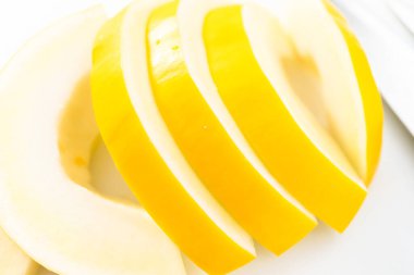 Beyaz kesme tahtasında kaygan altın çiğ taneli kavun.