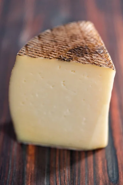 濃い木の背景に熟成したマンチェゴチーズの大きなくさび — ストック写真