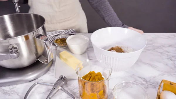 Mixing ingredients in electric kitchen mixer to bake pumpkin spice cupcake.