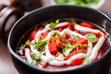 Ekşi krema ve maydanozla süslenmiş siyah bir kasede.