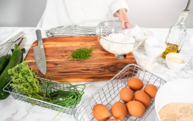 Kabak keki tarifi için tahta kesme tahtasıyla taze dereotu kesiyorum..