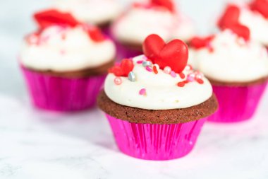 Krem peynirli kırmızı kadife kekler ve kalp ve öpücük şeklinde kırmızı çikolatalarla süslemeler..