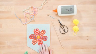 Anne çocuklara el sanatları masasında dikiş setiyle dikiş dikmeyi öğretiyor..