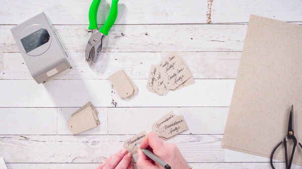 Flat lay. Step by step. Labeling brown paper gift tags with a black marker.