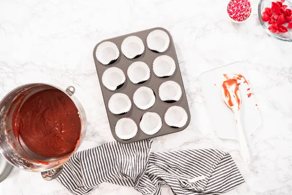 Flat lay. Flat lay. Lining cupcake pan with cupcake liners to bake red velvet cupcakes.