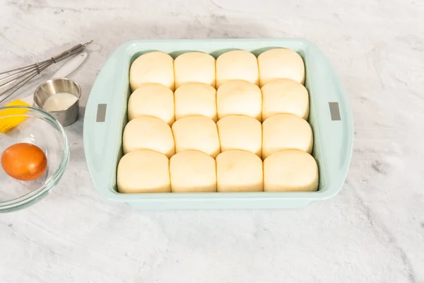 Preparing dinner rolls from the frozen dough in baking pan.