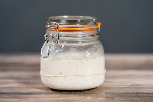 Кормление заварщика теста в стеклянной банке для выпечки ремесленного хлеба.