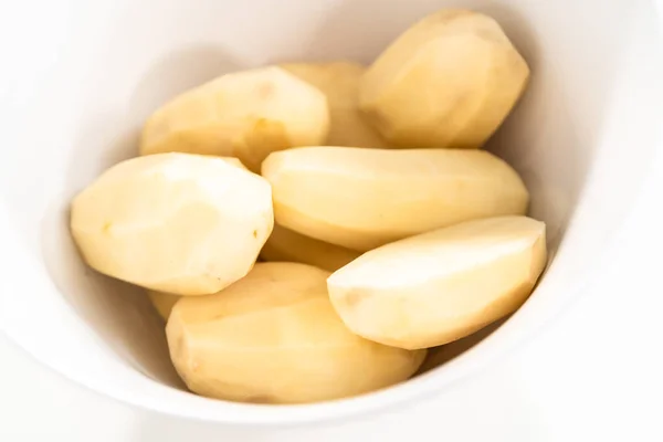 Große Gelbe Kartoffeln Schälen Mit Einem Gemüseschäler Auf Einem Weißen — Stockfoto