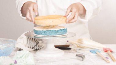 Yuvarlak üç katlı vanilyalı pasta yapmak için pasta katmanları yığılıyor.