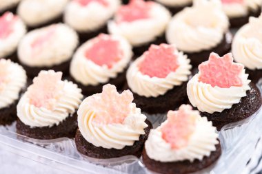 İtalyan tereyağı kremalı çikolatalı mini kekler. Parlak çikolatalı kar taneleriyle süslenmiş..