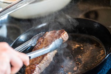 Elektrikli fırının üstünde kızgın demir tavayla New York bifteği kızartıyorum..