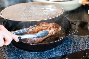 Elektrikli fırının üstünde kızgın demir tavayla New York bifteği kızartıyorum..