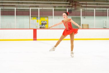 Genç kız buz pateni pistinde artistik patinaj yapıyor..