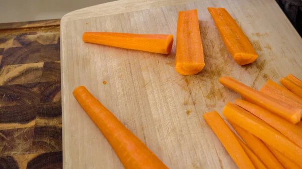 Ağaç kesme tahtasıyla büyük turuncu havuç kesiyor..