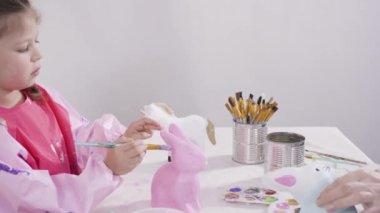 Akrilik boyayla resim yapan küçük bir kız..