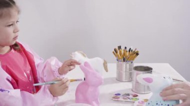 Akrilik boyayla resim yapan küçük bir kız..