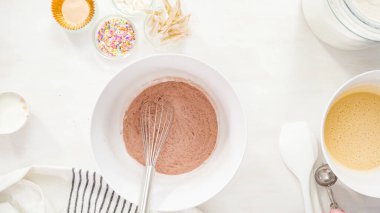 Düz yatıyordu. Adım adım. Tek boynuzlu at çikolatalı kekleri tereyağlı kremayla karıştırmak için karışımı beyaz bir kasede karıştırıyorum..