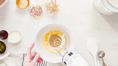 Düz yatıyordu. Adım adım. Tek boynuzlu at çikolatalı kekleri tereyağlı kremayla karıştırmak için karışımı beyaz bir kasede karıştırıyorum..