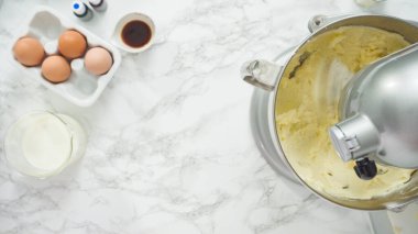 Adım adım. Düz yatıyordu. Üç katlı vanilyalı kek pişirmek için mutfak mikserinin malzemelerini karıştırıyorum..