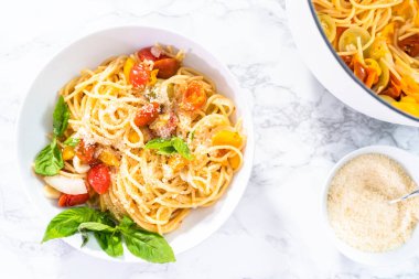 Kiraz domatesli vejetaryen makarna ve beyaz tabakta taze fesleğen..