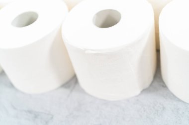 Gri arka planda yeni beyaz tuvalet kağıdı ruloları.