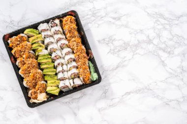 Düz yatıyordu. Önceden paketlenmiş suşi ve suşi çeşitleri plastik tepside..