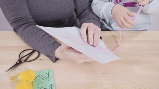 小さな女の子学ぶ方法とともに彼女のお母さんとともにザクラフトテーブル — ストック動画