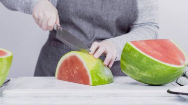 Kırmızı karpuzu beyaz bir kesme tahtasının üzerinde küçük parçalara ayırmak.