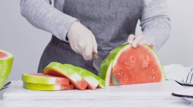 Kırmızı karpuzu beyaz bir kesme tahtasının üzerinde küçük parçalara ayırmak.