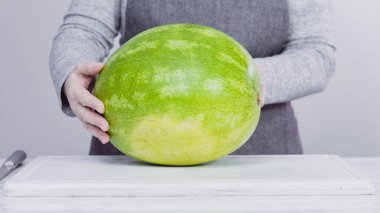 Kırmızı karpuzu beyaz bir kesme tahtasının üzerinde küçük parçalara ayırmak.