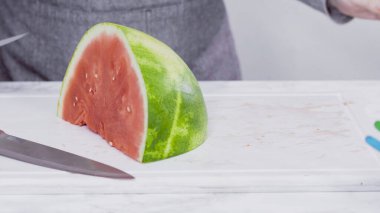 Kırmızı karpuzu beyaz bir kesme tahtasının üzerinde küçük parçalara ayırmak.