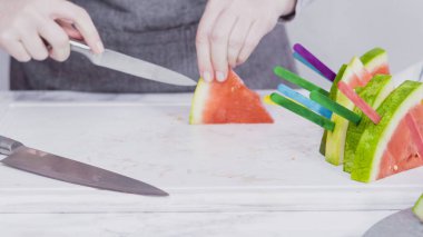 Kırmızı karpuzu beyaz bir kesme tahtasının üzerinde küçük parçalara ayırmak.