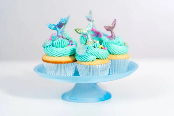ブルーのバタークリームがトッピングされたグルメマーメイドカップケーキで スプリンクルとチョコレートマーメイドの尾で飾られています — ストック写真
