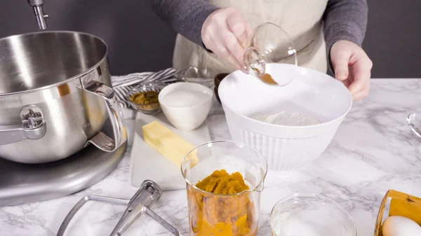 Mixing ingredients in electric kitchen mixer to bake pumpkin spice cupcake.