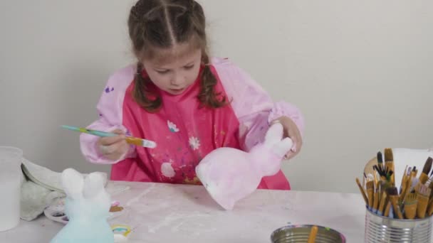 小さな女の子の絵画紙は彼女のホームスクーリングアートプロジェクトのためのアクリル塗料で人形をマッシュ — ストック動画