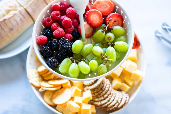 スモークサーモン チーズ クラッカー 新鮮な果物やベリーでいっぱいの白い層状のプレート — ストック写真